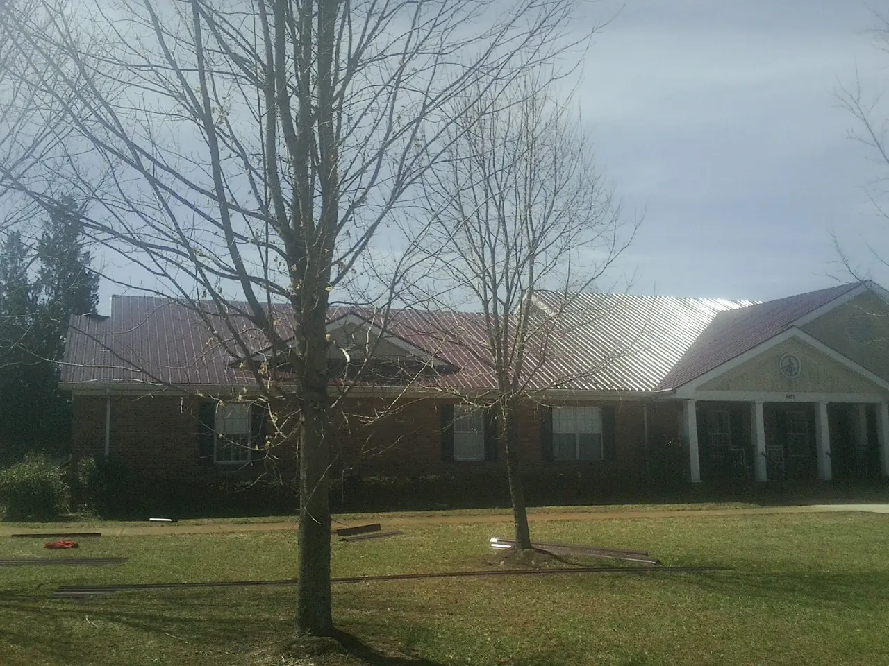Red metal roof on a brick building seen from the front lawn in Goehner
