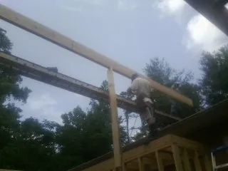 Carpenter setting a ridge beam over a new addition frame — Ice Dam Removal by Roofing Brothers in Goehner