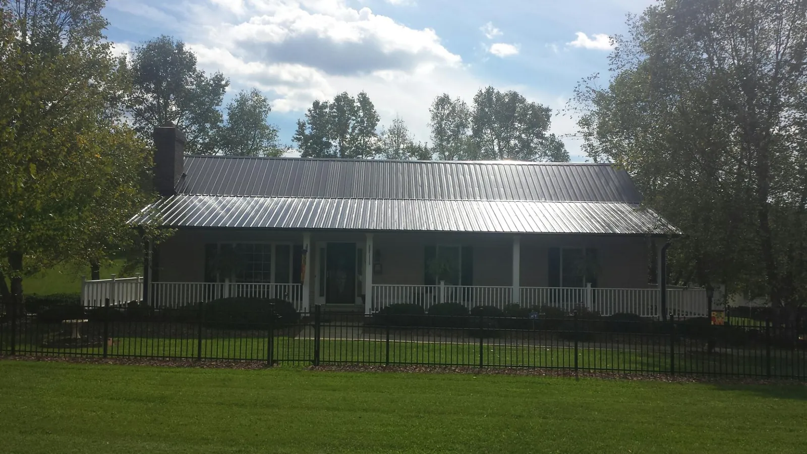 Gray metal roof on a brick ranch with a full width front porch — Gutter Guard Installation work by our crew in Goehner
