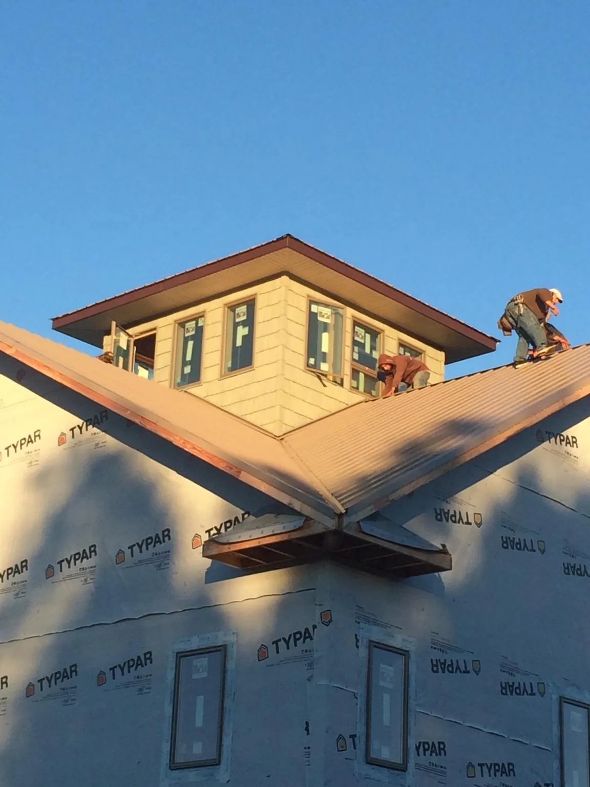 Roofers working around a rooftop cupola on a new metal roof at sunset — Roof Waterproofing in Goehner by Roofing Brothers